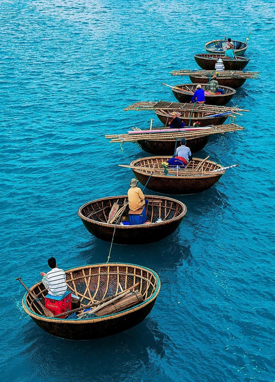 Fishermen in round bamboo basket boats on the turquoise sea in Vietnam